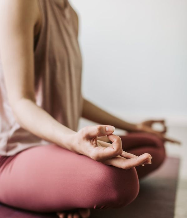 Woman in a calm seated yoga pose with golden light elements.